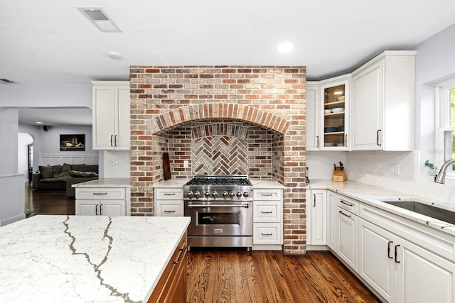 kitchen with visible vents, light stone countertops, tasteful backsplash, a sink, and stainless steel range