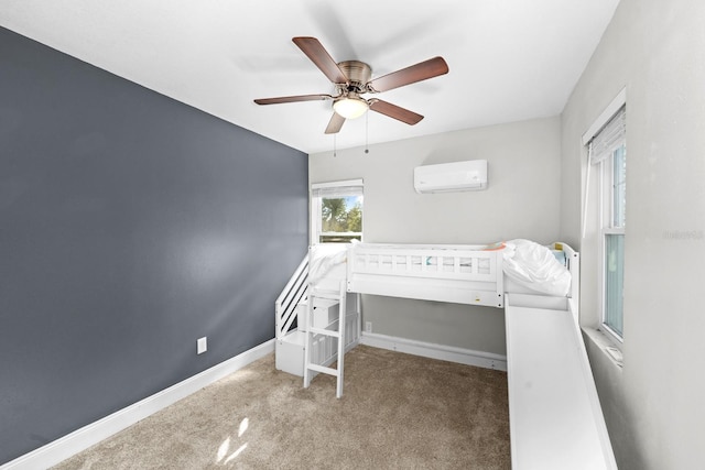 carpeted bedroom with a wall mounted AC, baseboards, and ceiling fan