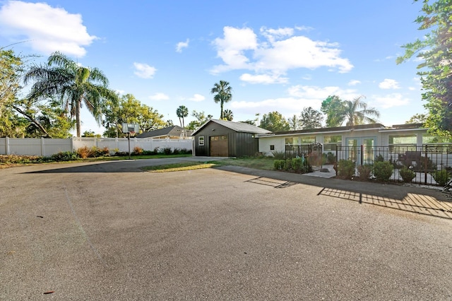 single story home with driveway, an outdoor structure, fence, and a garage