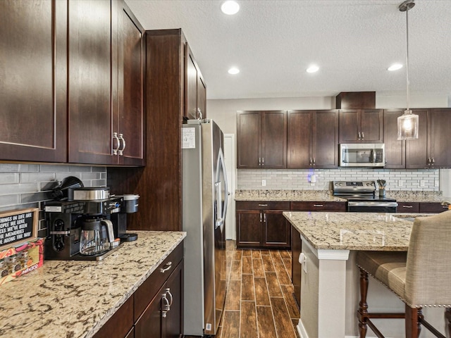 kitchen featuring tasteful backsplash, dark brown cabinets, appliances with stainless steel finishes, and wood finish floors