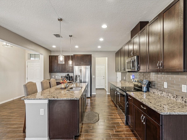 kitchen featuring dark brown cabinets, stainless steel appliances, visible vents, and wood tiled floor