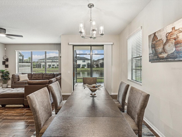 dining area with baseboards, a textured ceiling, wood finished floors, and ceiling fan with notable chandelier