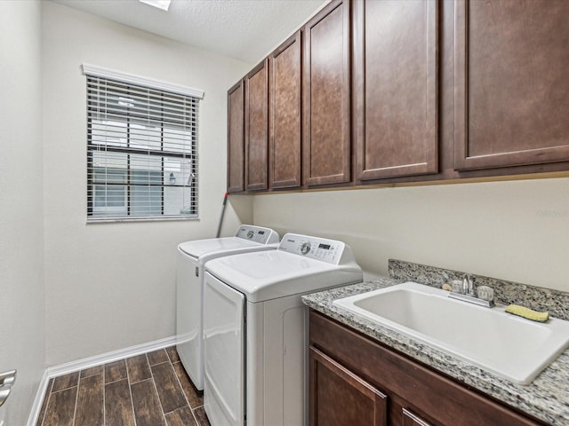 laundry area featuring baseboards, wood finish floors, cabinet space, a sink, and independent washer and dryer