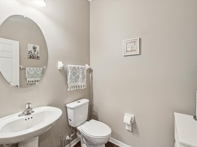 bathroom with toilet, baseboards, and a sink