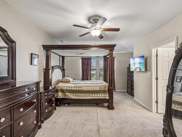 bedroom with a textured ceiling, ceiling fan, baseboards, and light carpet