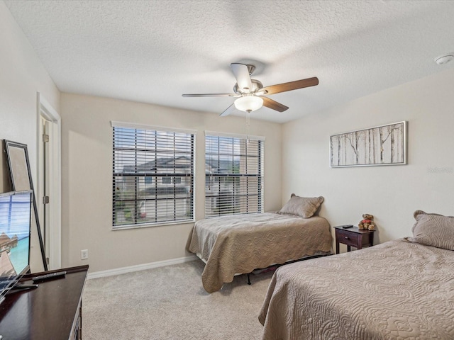 carpeted bedroom with a textured ceiling, baseboards, and ceiling fan