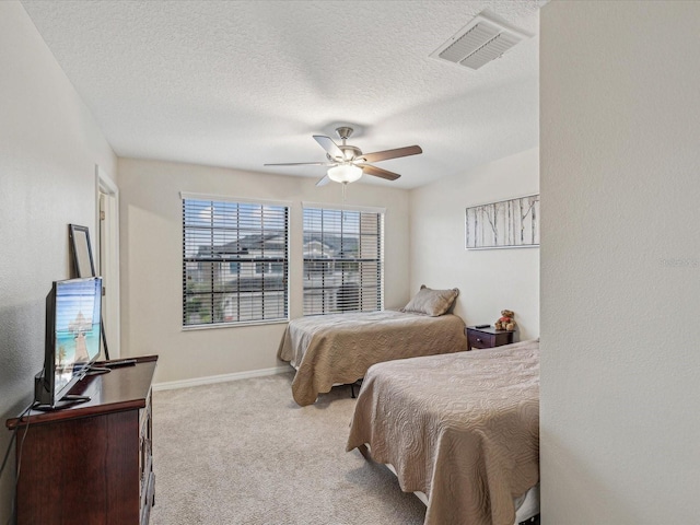 carpeted bedroom with baseboards, visible vents, a textured ceiling, and a ceiling fan