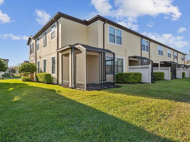 back of house with stucco siding, a residential view, a lawn, and fence