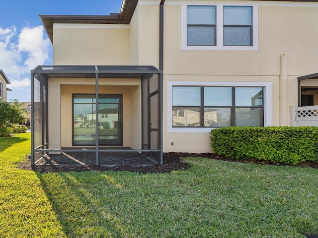 back of property with a lawn and stucco siding