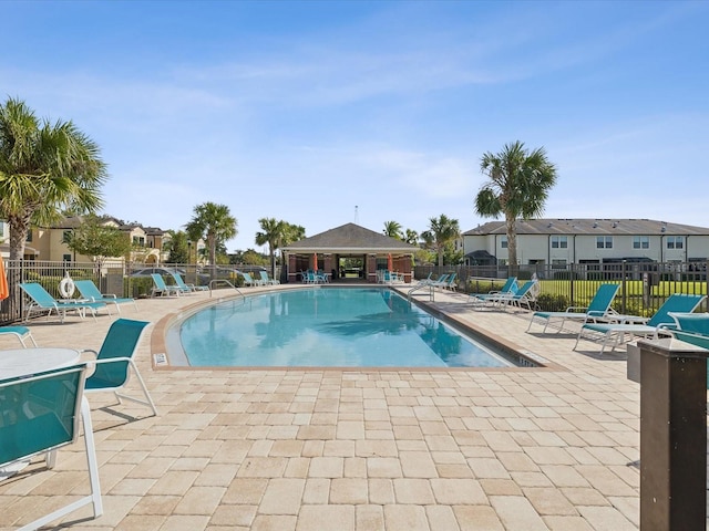 pool with a patio area, a residential view, and fence