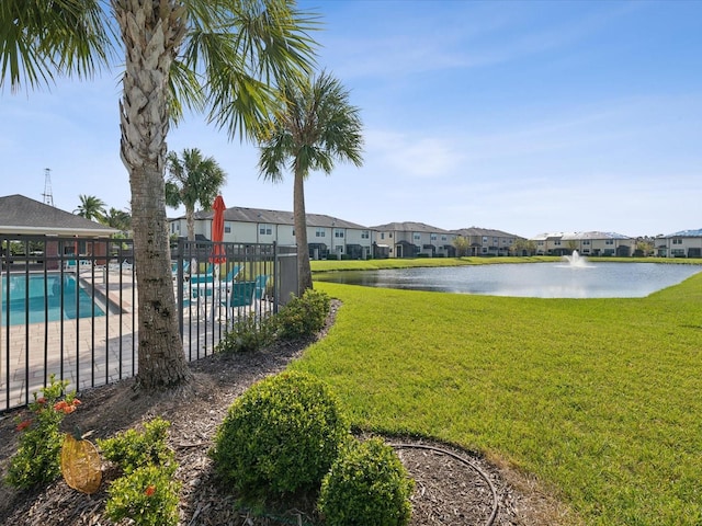 view of yard with a community pool, fence, a water view, and a residential view