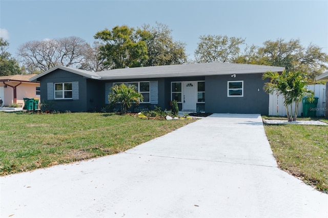 ranch-style house with a front lawn, concrete driveway, and stucco siding