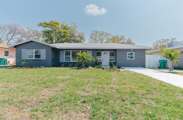 ranch-style house featuring brick siding, concrete driveway, a front yard, and fence