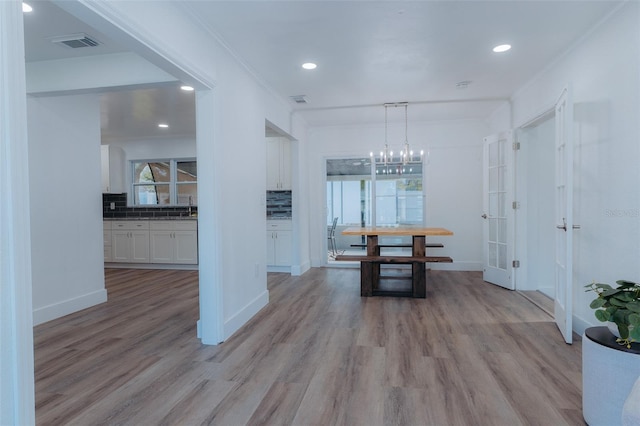 unfurnished dining area featuring light wood-type flooring, visible vents, baseboards, and crown molding