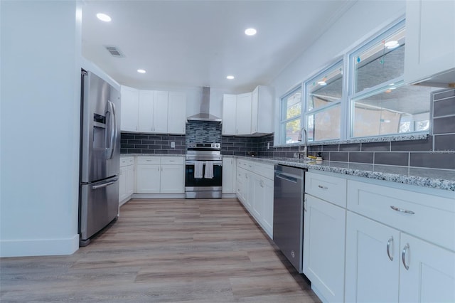 kitchen with visible vents, tasteful backsplash, appliances with stainless steel finishes, wall chimney exhaust hood, and light stone countertops