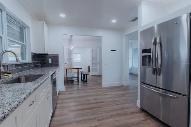 kitchen featuring backsplash, light wood-style floors, appliances with stainless steel finishes, and a sink