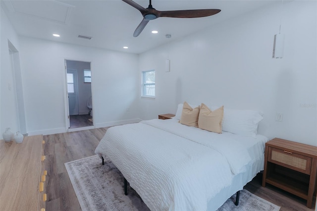 bedroom with wood finished floors, visible vents, baseboards, attic access, and recessed lighting