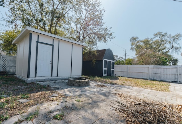 view of shed featuring a fenced backyard and a fire pit