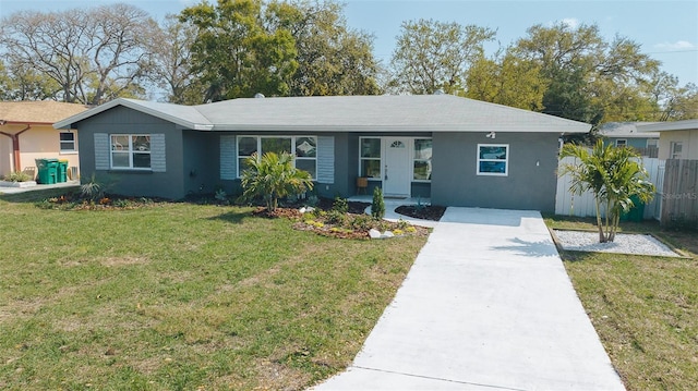 ranch-style home featuring stucco siding, driveway, a front yard, and fence