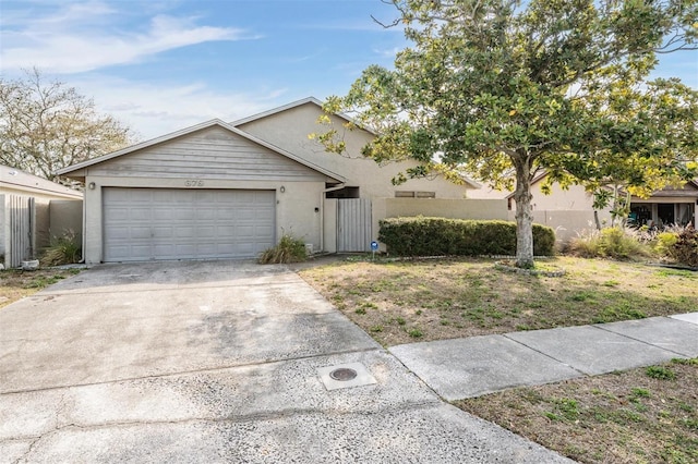 view of front of home featuring a garage, stucco siding, driveway, and fence