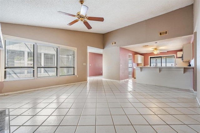 unfurnished living room featuring ceiling fan, visible vents, light tile patterned flooring, and vaulted ceiling