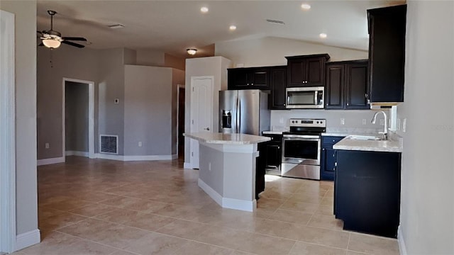 kitchen with visible vents, a kitchen island, stainless steel appliances, a ceiling fan, and a sink