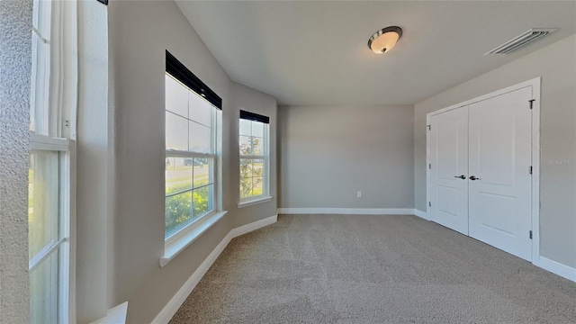 unfurnished bedroom with visible vents, baseboards, carpet, and a closet