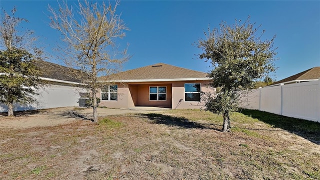 rear view of property with stucco siding, a fenced backyard, and a patio area