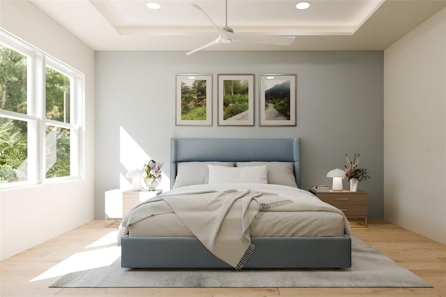 bedroom with a raised ceiling, multiple windows, wood finished floors, and recessed lighting