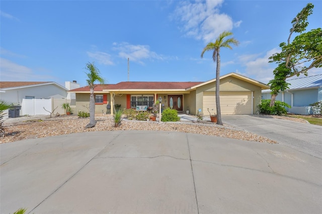 ranch-style home featuring stucco siding, an attached garage, concrete driveway, and fence