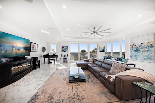 living area with recessed lighting, a raised ceiling, and a ceiling fan