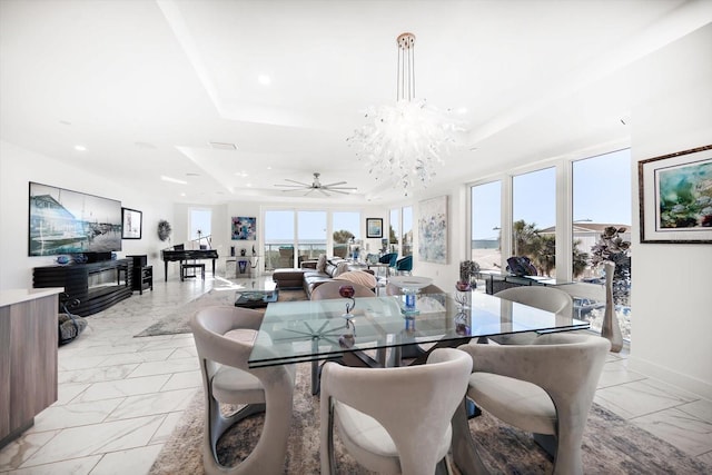 dining space with a raised ceiling, recessed lighting, a healthy amount of sunlight, and a chandelier