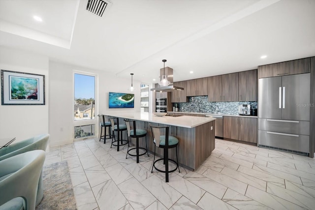 kitchen featuring a breakfast bar area, stainless steel appliances, light countertops, marble finish floor, and tasteful backsplash