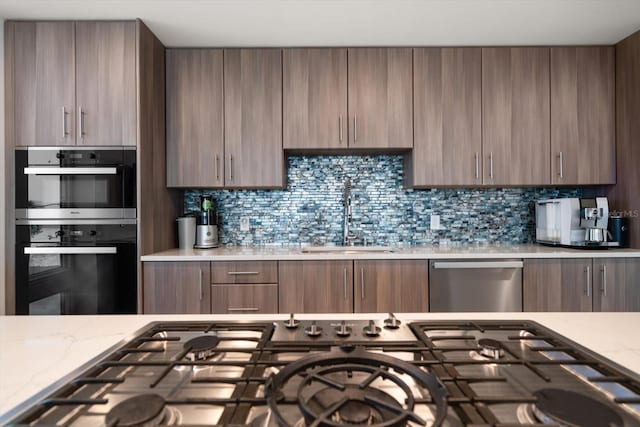 kitchen with backsplash, appliances with stainless steel finishes, modern cabinets, and a sink