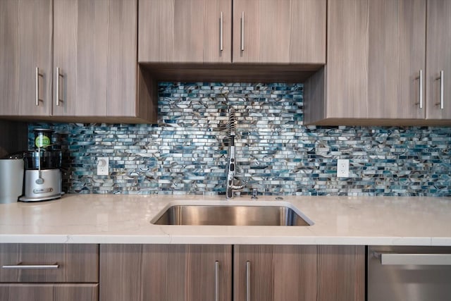 kitchen with light stone counters, modern cabinets, backsplash, and a sink