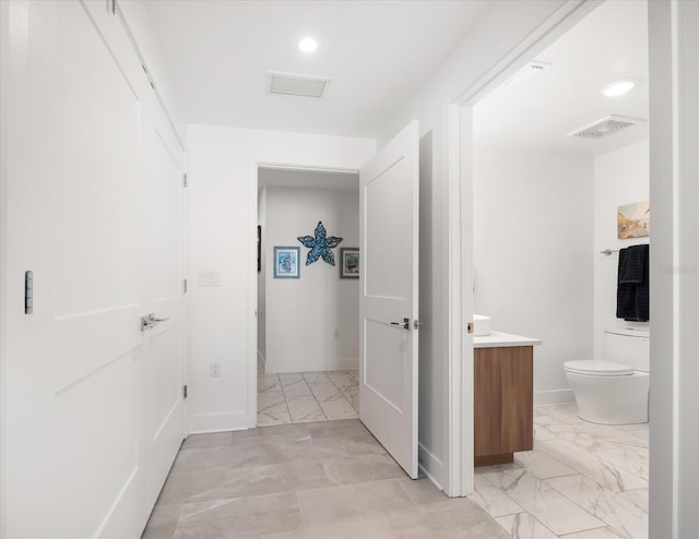 hallway with visible vents, marble finish floor, and baseboards