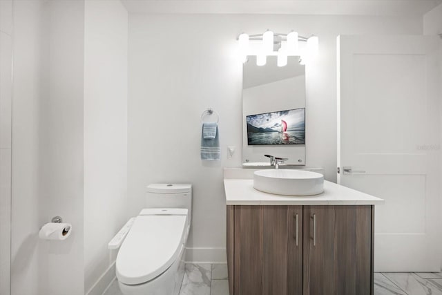 half bath featuring baseboards, toilet, marble finish floor, and vanity