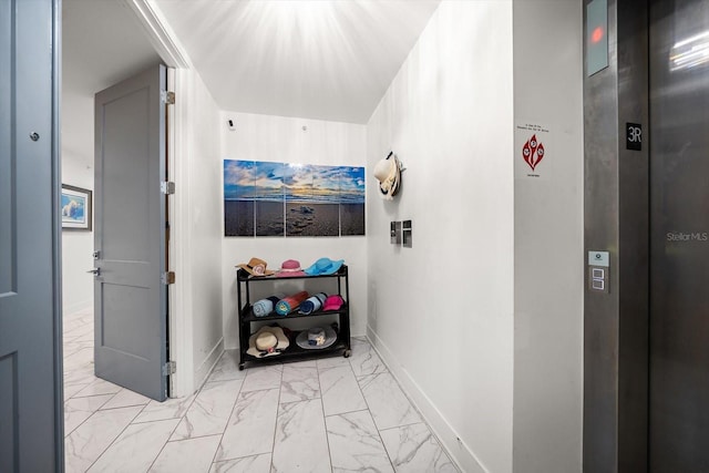 corridor with elevator, baseboards, and marble finish floor