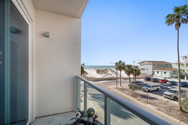 balcony featuring a view of the beach and a water view