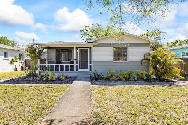 view of front facade featuring fence, a front yard, and a sunroom