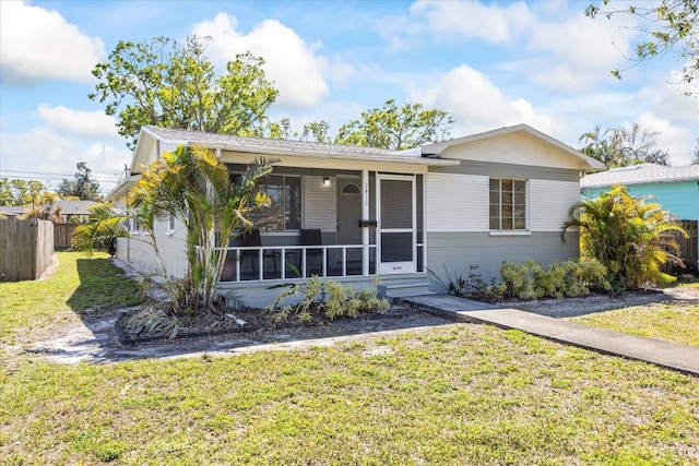 ranch-style home with a porch, a sunroom, a front lawn, and fence