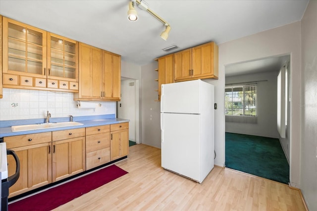 kitchen with visible vents, light wood-style flooring, freestanding refrigerator, a sink, and decorative backsplash