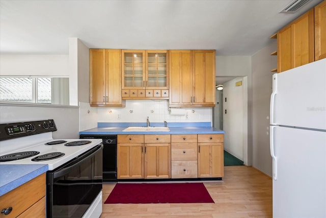 kitchen featuring visible vents, a sink, range with electric stovetop, freestanding refrigerator, and decorative backsplash