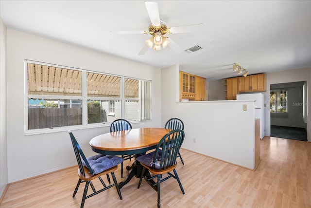 dining room with light wood finished floors, visible vents, ceiling fan, and baseboards