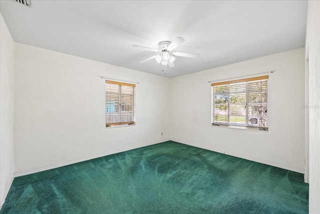 unfurnished room with a ceiling fan, a healthy amount of sunlight, and dark colored carpet