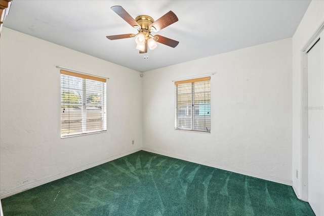 carpeted empty room featuring a healthy amount of sunlight, ceiling fan, and a textured wall