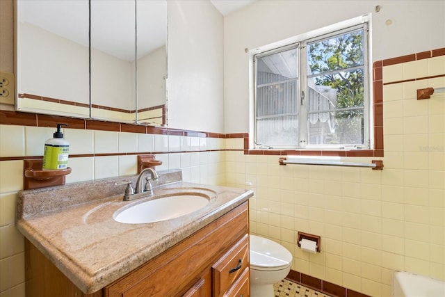 bathroom featuring toilet, tile walls, and vanity