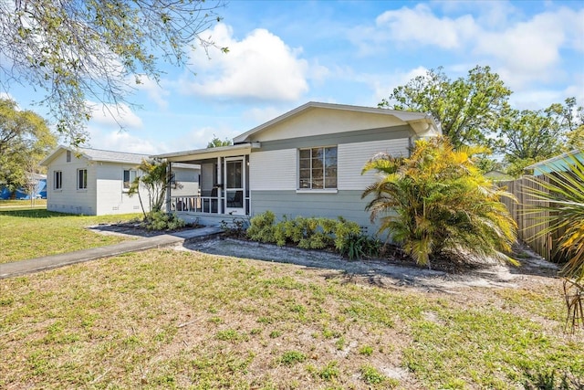 ranch-style home with a front yard, fence, and a sunroom