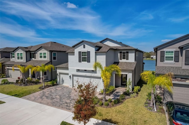 view of front of house with stucco siding, decorative driveway, a residential view, roof with shingles, and an attached garage