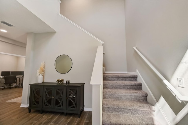 stairs featuring wood finished floors, baseboards, and visible vents